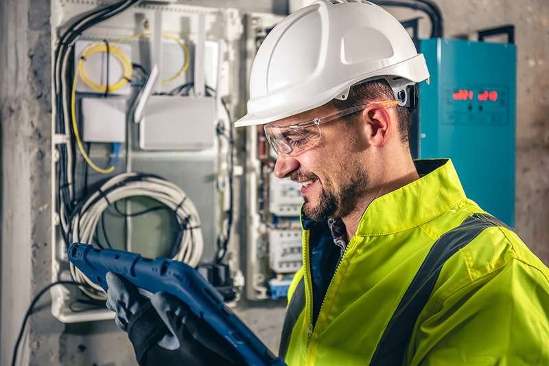 Técnico eletricista trabalhando em quadro elétrico com tablet